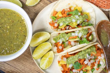 Platter of mexican al pastor tacos with lime and salsa verde