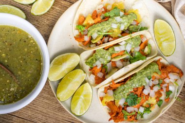 Overhead of tacos al pastor with lime and salsa verde