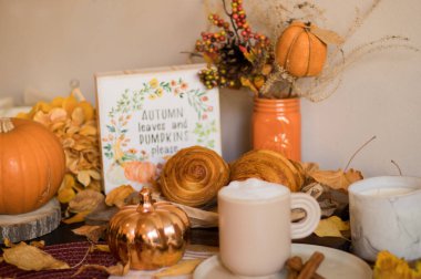 Sonbahar balkabağı, balkabağı, fındık, kruvasan ve bir fincan kahve beyaz ahşap arka planda.