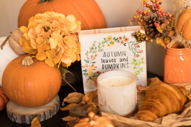 Sonbahar balkabağı, balkabağı, mumlar ve ahşap bir masada bir fincan kapuçino.