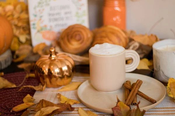 Sonbahar balkabağı, balkabağı, fındık, tarçın, kruvasan ve bir fincan kapuçino ahşap masada..