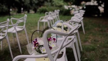 Parkta beyaz sandalyeli düğün kemeri.