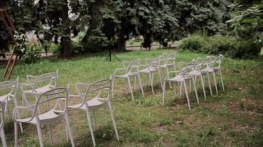 Düğün töreninin kemerinin yanındaki beyaz sandalyeler.