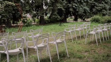 Düğün töreninin kemerinin yanındaki beyaz sandalyeler.