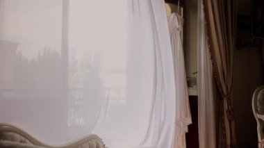 bride's white wedding dress hanging in the room