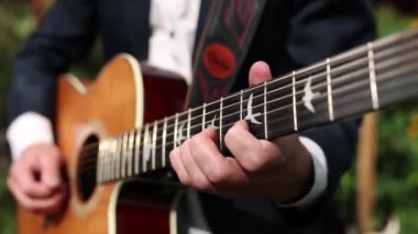 Sokakta ceketli gitar çalan bir adam.
