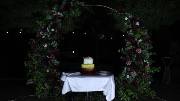 Белый Вкусный Свадебный Торт Вечером Возле Арки — стоковое видео