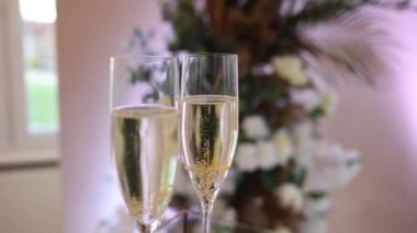 Çiçeklerin arka planında bir restoranda bir bardak şampanya.