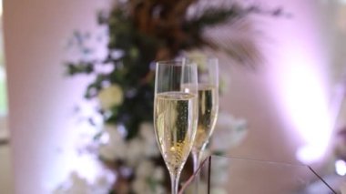 Çiçeklerin arka planında bir restoranda bir bardak şampanya.