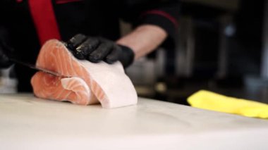 Mutfaktaki aşçı suşi için alabalık kesiyor.