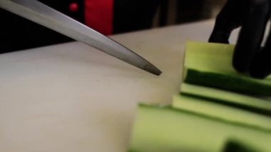 Aşçı mutfakta bıçakla taze salatalık keser.