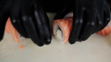Japon mutfağından bir erkek aşçı somonla bir rulo kesiyor.