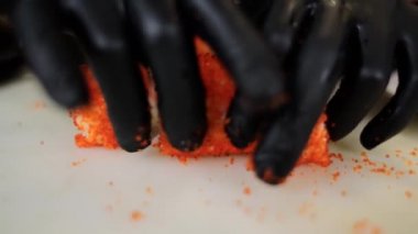 Erkek bir şef Japon suşisini kırmızı tobiko havyarına sarar.