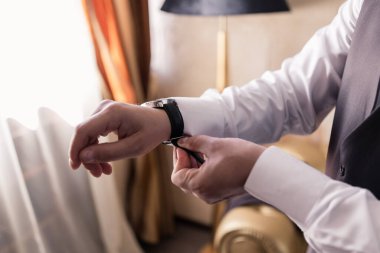 Bir adam eline saat takıyor.