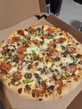 Zeytin ve sosis dolu bir kutuda büyük bir pizza.