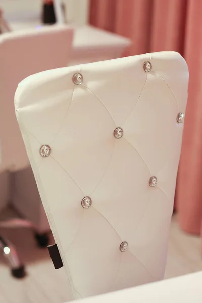 a white leather chair back with buttons in the room