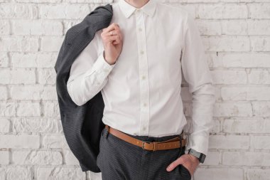 man in a white shirt and jacket near a brick wall