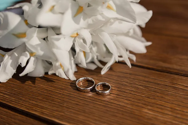 Goldene Eheringe Liegen Auf Einem Holztisch Mit Brautstrauß — Stockfoto