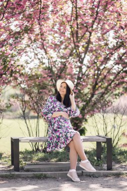 Bahçedeki sakura 'nın yanındaki elbisenin içinde hamile bir kız.