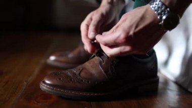 man tying shoelaces on brown leather shoes