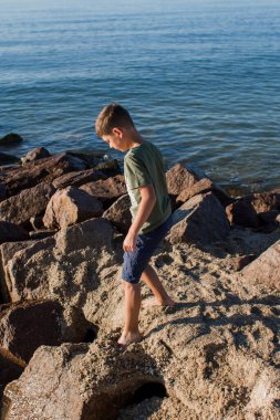 Sabahleyin kayalık sahilde bir çocuk