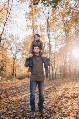 Sonbahar ormanında babasıyla portakal yapraklı bir çocuk.