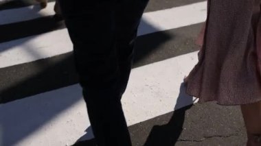 Bir kadınla birlikte bir adam, şehirde bir zebra geçidinde yürüyor.