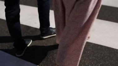 Bir kadınla birlikte bir adam, şehirde bir zebra geçidinde yürüyor.
