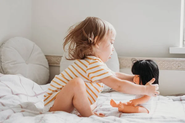 Маленькая девочка играет со своей куклой дома — стоковое фото