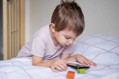 Anaokulu çocuğu evde akıllı telefonla oynuyor.