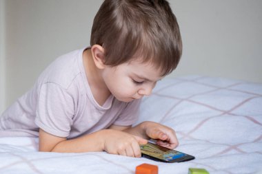 Anaokulu çocuğu evde akıllı telefonla oynuyor.