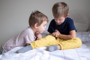 Evde akıllı telefonla oynayan iki anaokulu çocuğu.