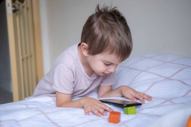 Anaokulu çocuğu evde akıllı telefonla oynuyor.