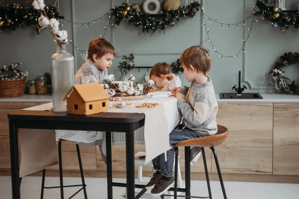 Küçük anaokulu çocukları Noel kurabiyelerini dekore ediyorlar.