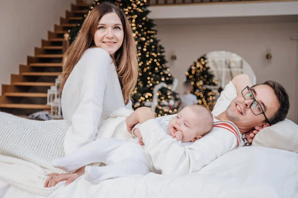 Χαρούμενη χαρούμενη καυκάσια οικογένεια με ουδέτερα ρούχα μαζί., Μητέρα, Πατέρας, κόρη και γιος ξαπλωμένοι στο κρεβάτι — Φωτογραφία Αρχείου