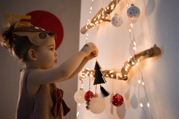 Evde Noel ağacı süsleyen küçük bir kız. Çevre dostu alternatif Noel ağacı