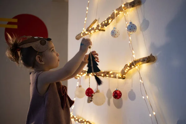 Evde Noel ağacı süsleyen küçük bir kız. Çevre dostu alternatif Noel ağacı