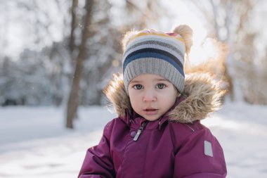 Kışın karlı ormanda karla oynayan küçük bir kız. Güneşli kış günü. Soğuk, karlı kış.