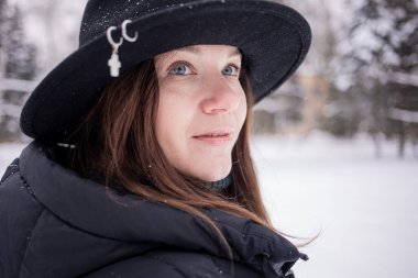 Kışın karlı ormanda siyah şapkalı beyaz bir kadın.. 