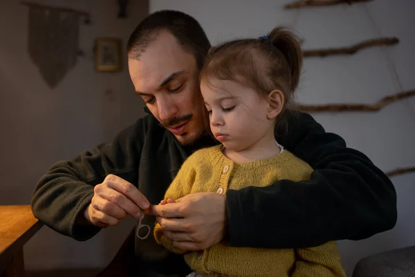 Człowiek pracujący na laptopie ze swoją małą córeczką na rękach. Ojcostwo, tata i córka razem — Zdjęcie stockowe
