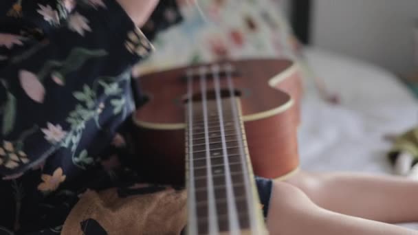 Niña jugando en ukelele guitarra a su peluche juguete amigo — Vídeo de stock