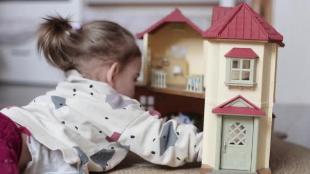 Niña jugando con casa de muñecas en casa — Vídeo de stock
