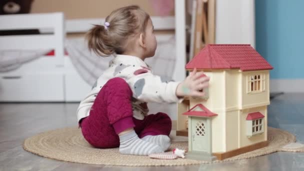 Maluch dziewczyna bawi się z dom lalki w domu — Wideo stockowe