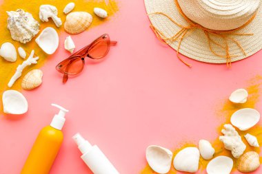 Plaj kumsalı ve deniz kabukları hasır şapka ve güneş kremi şişeleriyle