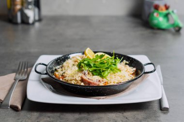 Risotto with porcini mushroom in the7 black metal pot on top with Arugula. High quality photo