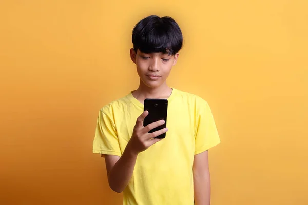 Портрет Азіатського Юнака Жовтій Футболці Виглядає Щасливим Бачить Новини Смартфона — стокове фото