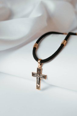 Gold cross on a black thread on a white background , religion 