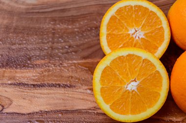 Ahşap arka planda tam ve dilimlenmiş portakallar ve sol tarafta ifade için yer var.