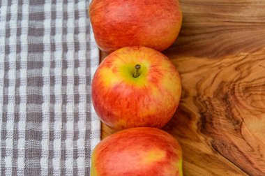 Elmalar ahşap arka planda, kumaş solda.