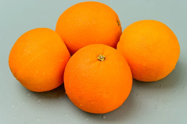 Four whole Oranges on a plain background